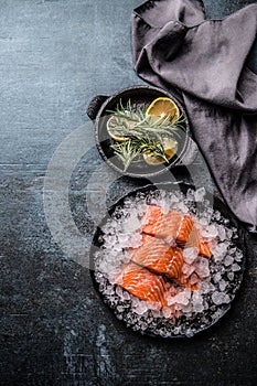 Portioned raw salmon fillets in ice on plate with lemon and rosemary