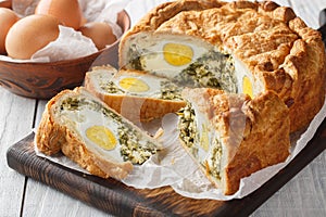 Portioned traditional Italian Easter cake or tart with spinach, ricotta and whole eggs closeup on the wooden board. Horizontal