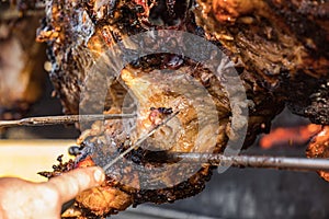 Portioning of roasted pig, slicing of meat. Pig grilled traditional coal and fire. The little pig is roasted whole on an open fire