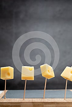 Portions cubes, dice of Emmental Swiss cheese punctured in toothpicks. Copy space