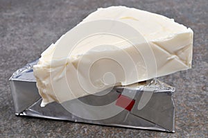 Portions of spreadable cheese including one open close-up on gray background