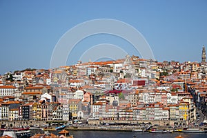 Porto panoramic landmark with boats on sunny day. Old buildings with brick roofs by river Douro in Porto, Portugal.