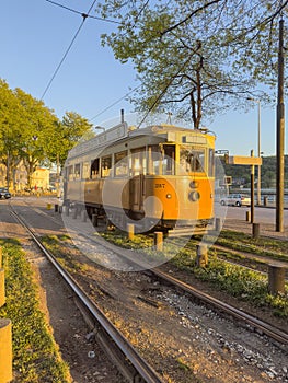 PORTO, PORTUGAL - CIRCA APRIL 2023: Wooden historical vintage yellow tram 287 moving on Porto street, symbol of city. Old tram