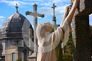 Porto, Portugal - A tomb statue standing on the knees and holding to the grave at Agramonte Cemetery, in the day light