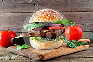 Portobello mushroom vegan burger on a wooden serving board against a dark wood background