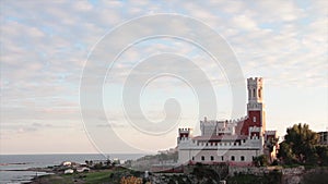 portopalo sicily italy red white castle shot from side next to water with clouds 447 v