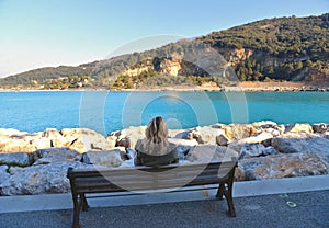 Portovenere, Italy  View on Palmaria island from Portovenere beach with young woman on the bench . Liguria italy