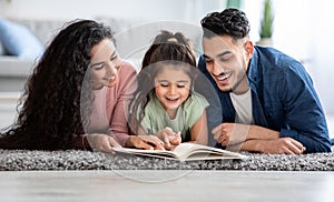 Portraif Of Happy Arabic Family Of Three Reading Book Together At Home