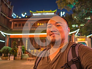 Portrail photo of asian man traveler in Huogongdian Food garden entrance Gate in Changsha city China.