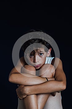 Portrait of a 10 year old boy looking sad, black background