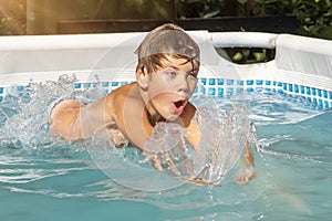 Portrait of a 10-year-old boy who dives into the water in an outdoor pool in the summer, water splashes, close-up, selective focus