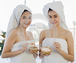 Portrait 2 asian adults women with covered by white towel on her head and  wearing white robes Smiling standing and holding wooden