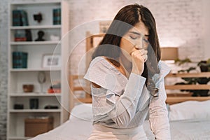 Portrait of 20s young Asian woman having dry cough in bedroom at home