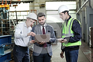 Portrait of a 3 men in a airplane manufactory. Two company managers and one factory worker deciding future plans.