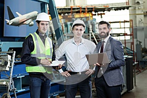 Portrait of a 3 men in a airplane manufactory. Two company managers and one factory worker deciding future plans.