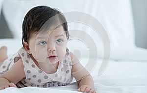 Portrait of 3 months old newborn baby in white bed. Innocent adorable Mixed race baby, Asian Caucasian, is lying or crawling.