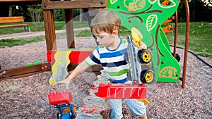 Portrait of 3 years old toddler boy taking his toys from sandbox in palyground