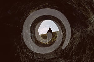 Portrait of a 30s man with a fedora and shirt at the entry of the Homer`s cave