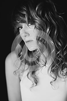 Portrait of a 36 year old woman with curly hair and brown slanting eyes. Soft selective focus. Black and white art photo