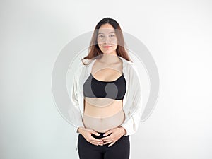 Portrait of 4 months pregnant Asian woman in white bed room, Woman touching her abdomen belly on white background.