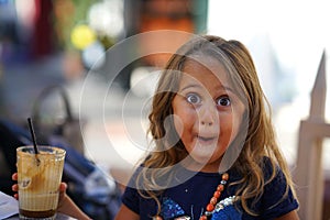 Portrait of 4 year old girl that makes the funny face drinking a decaf