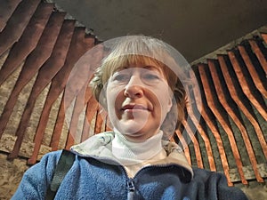 Portrait of 40-year-old woman with sport blue sweater. middle-aged blonde woman on the background of wooden slats in the