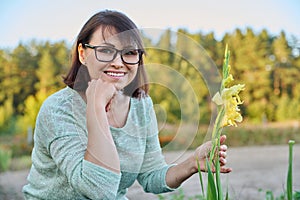 Portrait of 40s woman looking at camera with blooming flowers