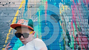 Portrait of a 5-year-old street dancer, A cool 5 year old child dances in sunglasses near a brick wall with graffiti