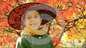 Portrait of 6 year old Halloween boy wearing witch hat in autumn park.