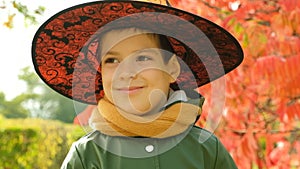 Portrait of 6 year old Halloween boy wearing witch hat in autumn park.