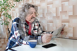 A portrait of a 60-year old man reading news. A newspaper in a pensioners hands