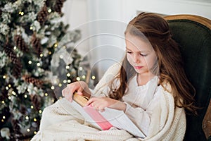 Portrait of 7 years old child reading book at home on christmas
