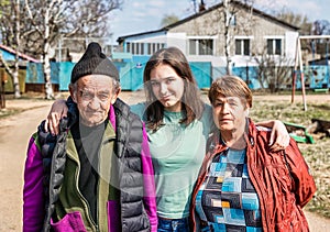 Portrait of 75 years old grandparents and their granddaughter in russian village together