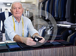 Portrait of an accomplished tailor with samples of fabric in atelier