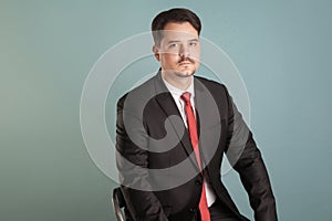 Portrait of acting shoot sitting businessman lookking seriously