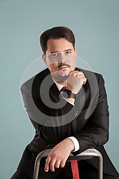Portrait of acting shoot sitting businessman touching chin, look