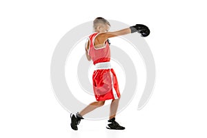 Portrait of active boy, beginner boxer in sports gloves and red uniform isolated on white background. Concept of sport