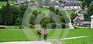 Portrait of active elderly couple hiking together in mountains. Senior tourists walking with trekking poles. Banner with