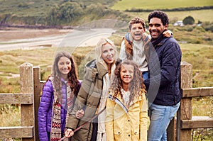 Portrait Of Active Multi-Cultural Family Standing By Gate On Winter Beach Vacation