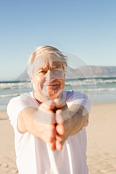 Portrait of active senior man practicing yoga at beach