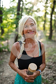 Portrait of active senior woman runnerwith water bottle outdoors in forest.