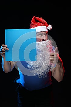 Portrait actor male in cap and beard of Santa Claus with a sheet of paper for notes in the hands