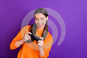 Portrait of addicted crazy funny funky teenager girl use her smartphone play game wear orange sportswear isolated over