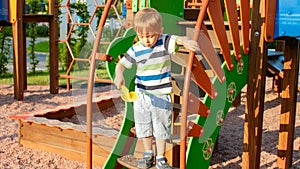 Portrait of adorable 3 years old boy climbing on ladder on the children palyground at park