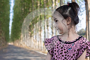 Portrait of adorable 5 years old asian posting for her cute face in beautiful park with perspective view of concrete road as