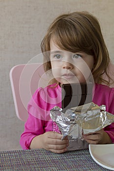 Portrait of an adorable baby girl eating chocolate.