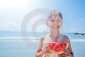Portrait of Adorable boy with watermelon on the beach.