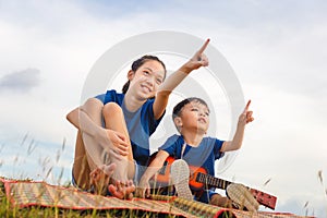 Portrait of adorable brother and sister playing outdoors. Happy kids boy and girl with guitar having fun outdoor