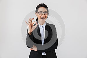 Portrait of adorable businesswoman 30s in formal wear and eyeglasses standing in the office, isolated over white background