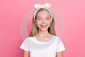 Portrait of adorable cheerful girl toothy smile peeling lotion cream face under eye isolated on pink color background